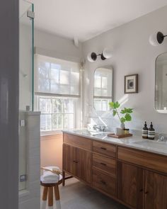 a bathroom with two sinks and mirrors on the wall, along with a wooden stool