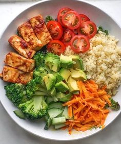 a white bowl filled with rice, broccoli, carrots and tofu