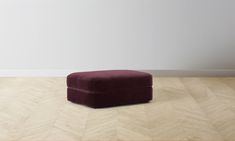 a foot stool sitting on top of a hard wood floor next to a white wall