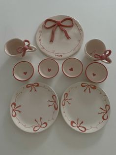 a set of pink and white dishes with bows on them