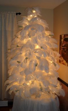 a white christmas tree decorated with lights and feathers