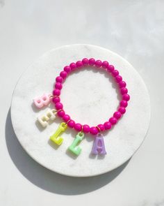 Introducing our delightful Personalised Multicoloured Name Children's Bracelets, a whimsical accessory that will bring joy and style to your little one's wrist!  These charming bracelets are a perfect blend of vibrant colours and playful customisation, making them an ideal bespoke gift for any special occasion. Each bracelet is beautifully adorned with adorable iridescent letter charms that hang and dangle gracefully from delicate gold hoops, adding a touch of elegance to the design. The best pa Personalized Pink Name Bracelet For Party Favors, Personalized Pink Novelty Bracelets, Cute Name Bracelet With Colorful Beads, Custom Name Pink Charm Bracelet, Personalized Pink Novelty Charm Bracelet, Customizable Pink Fun Bracelets, Pink Novelty Stretch Bracelet For Birthday, Novelty Pink Stretch Bracelet For Birthday, Fun Pink Adjustable Name Bracelet