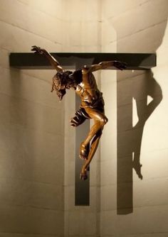 a sculpture of a man on a cross in the middle of a room with white walls