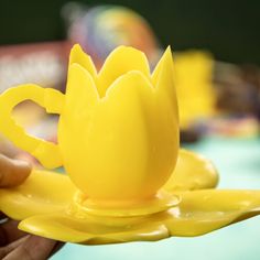 a person holding a yellow plastic cup and saucer