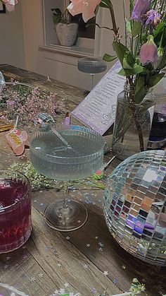 a table topped with lots of glass vases filled with flowers and confetti