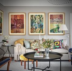 a living room filled with furniture and paintings on the wall above it's coffee table