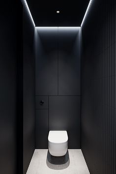 a white toilet sitting inside of a bathroom next to a black and white tiled wall