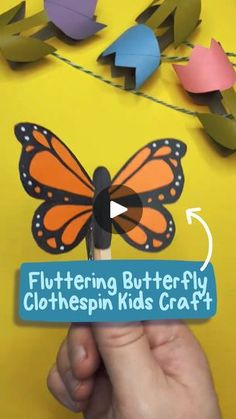 a hand holding a paper cutout of a butterfly with the words flutterering butterfly clothespin kids craft on it