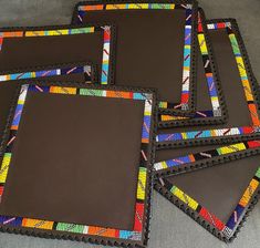 four brown and multicolored coasters sitting next to each other on a gray surface