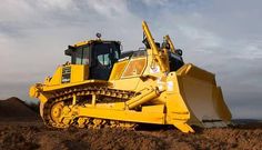 a large yellow bulldozer sitting on top of a dirt field