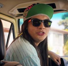 a woman wearing sunglasses and a green hat sitting in the passenger seat of a car