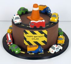 a birthday cake with cars and traffic signs on it's side, sitting on top of a black plate