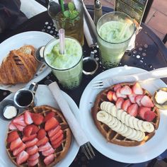 two waffles with strawberries, bananas and other food on them are sitting on a table