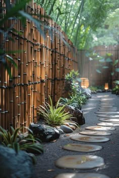 a bamboo fence with stones and plants in the foreground, next to a path