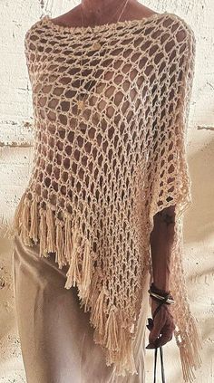 a woman is wearing a crocheted shawl and holding a purse in her hand