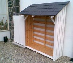 a dog house built into the side of a building with a black roof and white walls