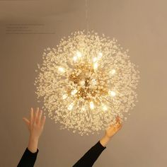 a person reaching up to a chandelier with lights on it