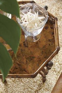 a glass bowl sitting on top of a wooden table next to a green leafy plant