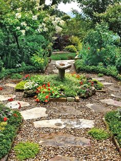 a garden with lots of plants and flowers on it's sides, including a stone bench in the middle