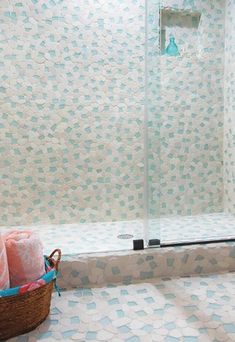 a bathroom with blue and white tiles on the shower wall, toiletries in a basket next to it