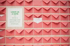 some pink origami pieces with a note attached to them and a sign that says leave us a note write a message and place in an envelope