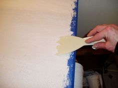 a person using a paint brush to paint a wall with white paint on the walls