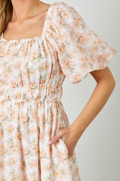 Expertly crafted for style and comfort, our Blossom Floral Print Midi Dress in Peachy is perfect for any occasion. Featuring charming puff sleeves, a flattering elastic waist, and convenient pockets, this dress effortlessly combines classic elegance with modern functionality. The square neck adds a touch of sophistication, making it a must-have for any wardrobe. square neckline puff sleeves elastic waist lined 100% polyester true to size model is wearing a medium Spring Peach Dress With Smocked Back, Feminine Dresses With Elastic Sleeves And Square Neck, Modest Puff Sleeve Spring Dress, Feminine Spring Puff Sleeve Dress With Elastic Sleeves, Pink Spring Dresses With Elastic Waistband, Feminine Puff Sleeve Dress With Smocked Back, Feminine Puff Sleeve Dress With Elastic Sleeves For Spring, Spring Midi Dress With Gathered Waist And Square Neck, Spring Midi Dress With Square Neck And Gathered Waist