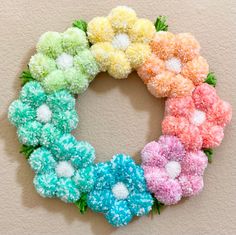 a wreath made out of different colored pom - poms on a white wall