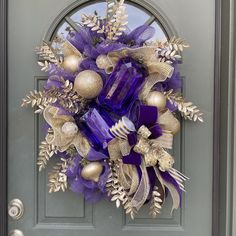 a purple and gold christmas wreath on the front door