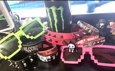 several bracelets and sunglasses are sitting on a table next to a cup with a monster logo