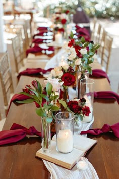 a long table is set with candles and flowers in vases on top of napkins