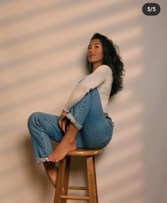 a woman sitting on top of a wooden stool