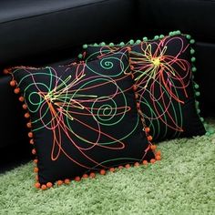 two black and orange pillows sitting on top of a green carpet