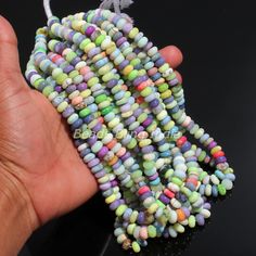 a hand holding a string of multicolored beads