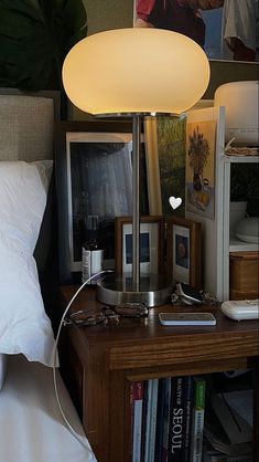 a lamp that is sitting on top of a table next to a book shelf and bed