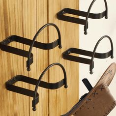 three pairs of shoes hang on the wall next to a pair of cloggers