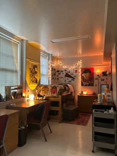 a room with two desks, chairs and pictures on the wall above them is lit by candles