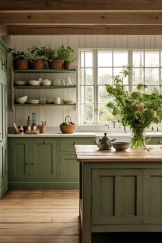 a kitchen filled with lots of green cupboards next to a wooden counter topped with pots and pans