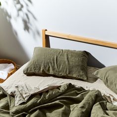 an unmade bed with green sheets and pillows