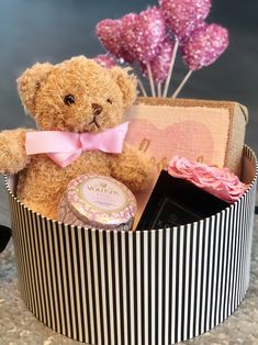 a teddy bear in a striped box with pink flowers