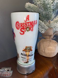 a christmas story glass sitting on top of a table next to a potted tree