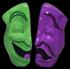 two green and purple masks with faces painted on each one's face, side by side