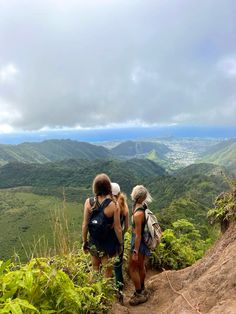 two women hiking up the side of a mountain with lush green hills in the background