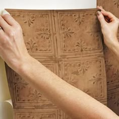 a woman is painting the wall with brown paint