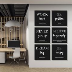 four black and white posters on the wall above a desk with a laptop in front of it