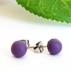 two purple balls are sitting next to each other on a white surface with a green leaf in the background