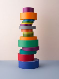 a stack of multicolored paper stacked on top of each other in front of a white wall