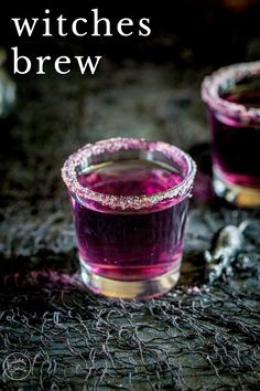 two glasses filled with purple liquid sitting on top of a black cloth covered tablecloth