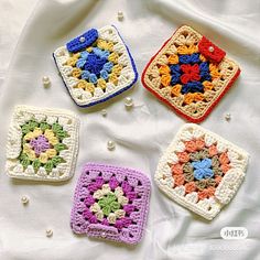 four crocheted squares are arranged on a white sheet