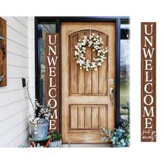 a front door with a welcome sign and potted plants on the porch next to it